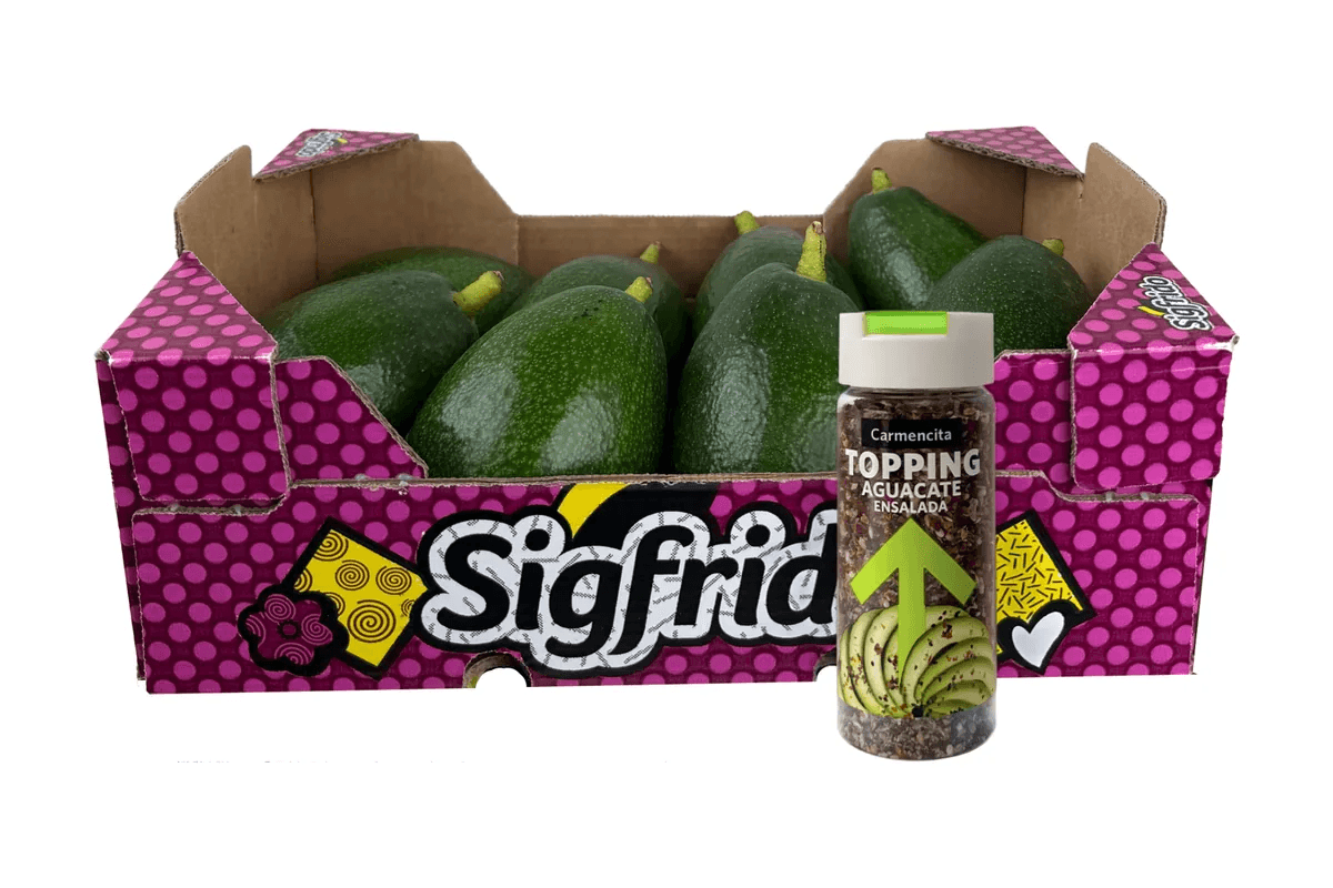 Aguacates Bacon de piel lisa con su pedúnculo en una caja Sigfrido de lunares fucsia, junto a un topping para aguacate de Carmencita